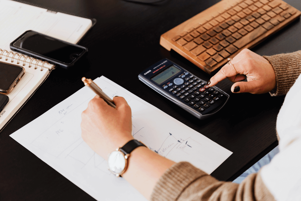 A person working on a calculator and writing something down